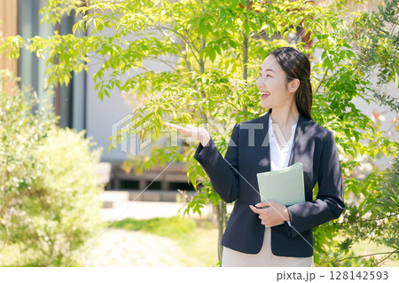 一軒家の前に立つスーツの女性 128142593