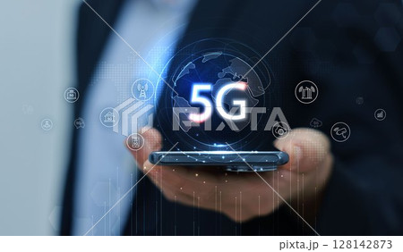 Hand holding smartphone with 5G icon and global network interface, representing high-speed wireless technology, digital connectivity, IoT, and future communication concept. communication network. 128142873