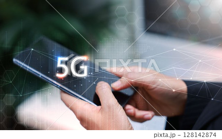 Hand holding smartphone with 5G icon and global network interface, representing high-speed wireless technology, digital connectivity, IoT, and future communication concept. communication network. 128142874