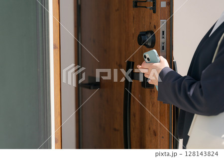 ドアの施錠をするスーツの女性 ドアの施錠をするスーツの女性 128143824