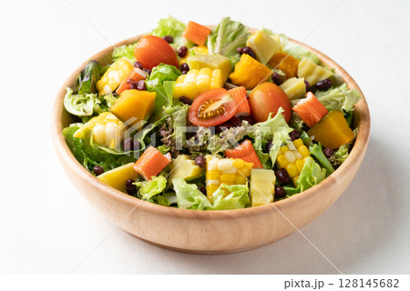 Colorful vegetable salad in a rustic wooden bowl on white background 128145682