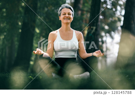 Smiling Woman in Sukhasana Pose Meditating with Joy in Nature during Outdoor Yoga Practice 128145788
