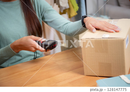 Closeup hand of woman scanning package with barcode reader in office, online seller. Closeup hand of woman scanning package with barcode reader in office, online seller. 128147775