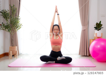 Young asian woman meditation sitting on mat in serene and tranquility with yoga in living room. 128147803