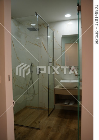 Modern Bathroom with Glass Shower and Marble Walls 128148901