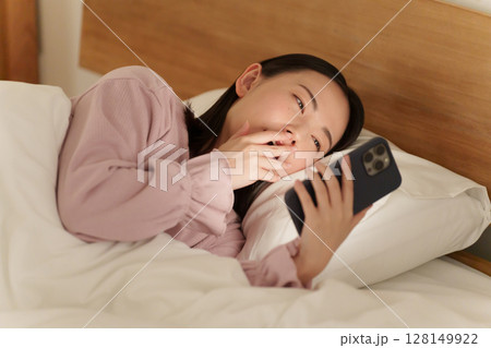 夜ベッドでスマホを使う女性 128149922
