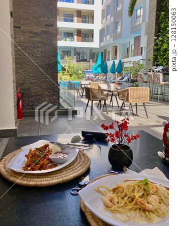 lunch on the terrace in an apartment overlooking the relaxation area and pool, summer holidays 128150063