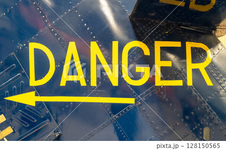 Yellow -Danger- warning sign on blue metallic aircraft fuselage panel Yellow -Danger- warning sign on blue metallic aircraft fuselage panel 128150565