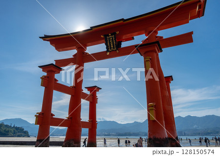 Close-up view of the famous Itsukushima shrine red torii gate and people walking on the beach in Miyajima, Japan 128150574