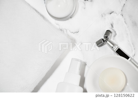 大理石の上に配置した白いタオルと美顔器とコスメ 128150622