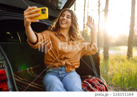 Happy Woman is resting in trunk of car and taking selfie. Selfie time. Lifestyle, travel Happy Woman is resting in trunk of car and taking selfie. Selfie time. Lifestyle, travel 128151164