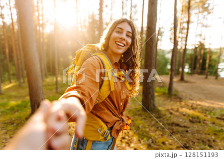 Traveling together. Happy woman holds the boyfriend's hand and walking on the forest. Vacation 128151193
