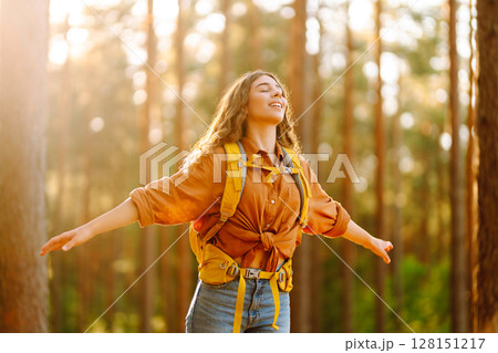 Tourist woman hiking alone in thick autumn forest. Stylish female looks for pathway among trees. Tourist woman hiking alone in thick autumn forest. Stylish female looks for pathway among trees. 128151217