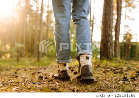 Feet of an adult wearing boots to travel walking in the forest. Feet walking in outdoor nature 128151269