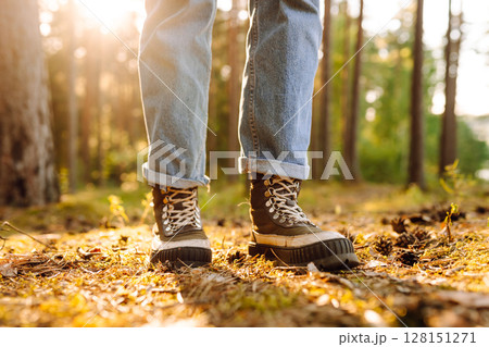 Feet of an adult wearing boots to travel walking in the forest. Feet walking in outdoor nature Feet of an adult wearing boots to travel walking in the forest. Feet walking in outdoor nature 128151271