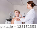 Cosmetic dermatologist drawing face lifting lines on mature woman in beauty clinic. Anti-aging consultation, aesthetic treatment planning, professional skincare procedures, non-surgical facelift 128151353