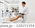 Cosmetologist using skincare equipment for photorejuvenation facial treatment. Mature woman lying on chair in beauty clinic before non-invasive anti-aging procedure with aesthetic laser technology 128151354