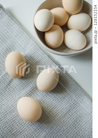 Fresh farm chicken eggs in a bowl and on a kitchen grey towel Fresh farm chicken eggs in a bowl and on a kitchen grey towel 128152154