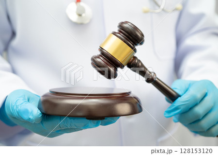 Asian doctor holding court hammer for and crime law justice, forensic medicine. Asian doctor holding court hammer for and crime law justice, forensic medicine. 128153120