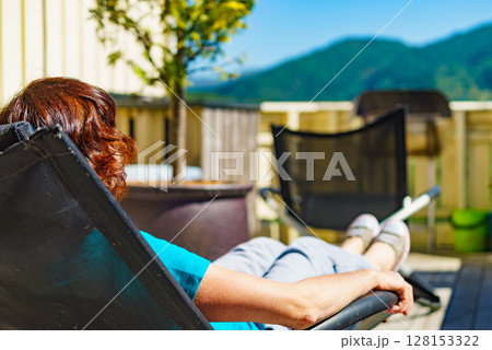 Woman relaxing in chair on veranda. 128153322