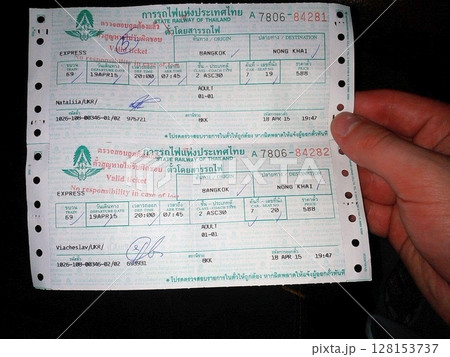 Two train tickets from the State Railway of Thailand for an express train from Bangkok to Nong Khai, dated 19 April 2015, held by a hand 128153737