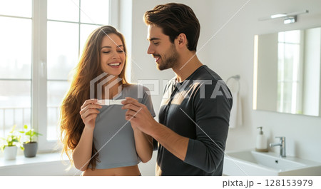 A couple looking at a pregnancy test together, sharing a joyful and emotional moment. The concept of partnership, new life, and the beginning of parenthood. Generative AI. 128153979