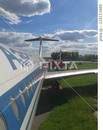 Side View of a Commercial Jet with Blue and White Design Parked in an Open Grassy Area 128153989