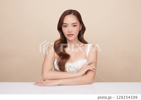 A beautiful young Asian woman with clean, fresh skin against a beige background. Skincare, facial treatment, cosmetology, beauty, and spa. An elegant portrait of an Asian woman. A beautiful young Asian woman with clean, fresh skin against a beige background. Skincare, facial treatment, cosmetology, beauty, and spa. An elegant portrait of an Asian woman. 128154109