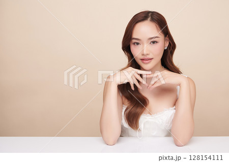 A beautiful young Asian woman with clean, fresh skin against a beige background. Skincare, facial treatment, cosmetology, beauty, and spa. An elegant portrait of an Asian woman. A beautiful young Asian woman with clean, fresh skin against a beige background. Skincare, facial treatment, cosmetology, beauty, and spa. An elegant portrait of an Asian woman. 128154111