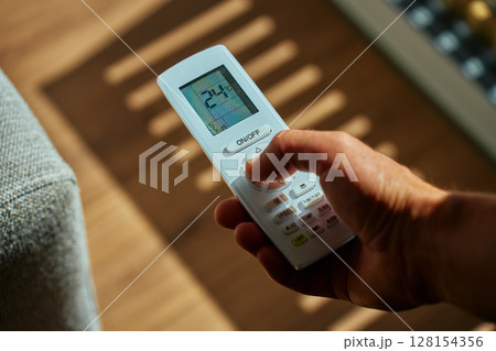 Air conditioner remote control in hand, close up 128154356
