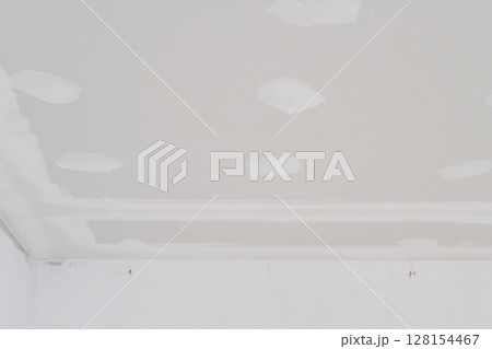 Inside building undergoing interior renovation gypsum board ceiling with electrical wire installation shows smooth edges and areas ready for plastering creating smooth finish 128154467