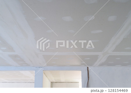 Building interior renovation showing gypsum board ceiling prepared. Smooth plastering applied to edges joints. Electrical wire present. Work creates smooth ceilings, sign of progress 128154469