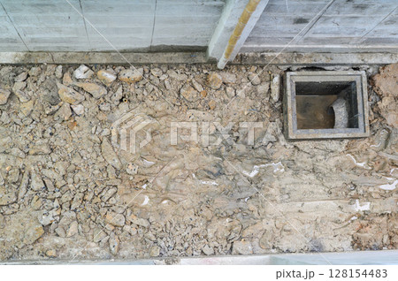 Unfinished floor during major house renovation project. ground shows exposed soil rock and new drain installation for construction site feeling of progress Unfinished floor during major house renovation project. ground shows exposed soil rock and new drain installation for construction site feeling of progress 128154483