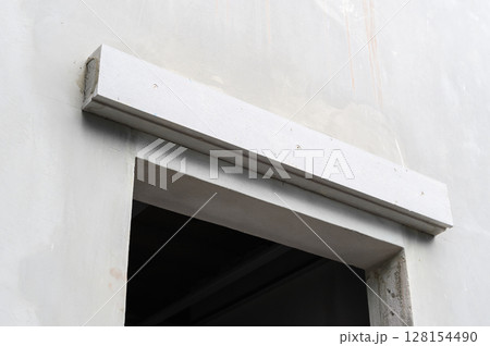 White architectural lintel installation over window opening on concrete wall. Close up detail of building site during thoughtful house renovation and construction 128154490