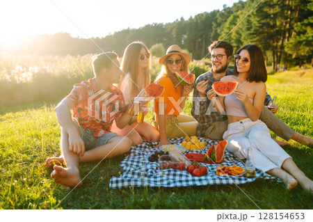 Group of people gathered in garden for picnic. Friends have fun and drink beer. Picnic, friendship. 128154653