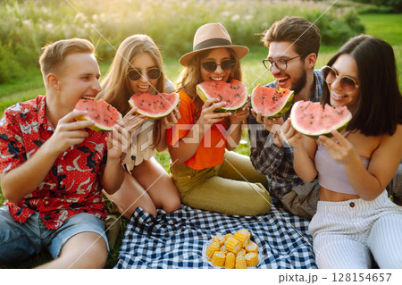 Group of people gathered in garden for picnic. Friends have fun and drink beer. Picnic, friendship. Group of people gathered in garden for picnic. Friends have fun and drink beer. Picnic, friendship. 128154657