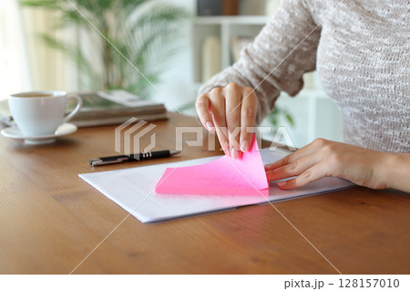 Woman hand removing sticky note from paper at home 128157010