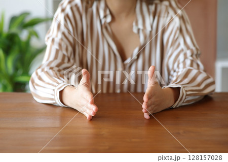 Woman hands gesturing measurement on a wooden table 128157028