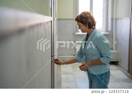 Woman opening the door to her office at the start of the workday. Entry, new beginning, and everyday professional routine. Woman opening the door to her office at the start of the workday. Entry, new beginning, and everyday professional routine. 128157118