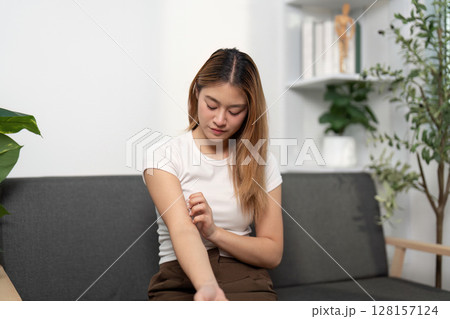 Health Awareness: Young woman examining her arm for discomfort. 128157124