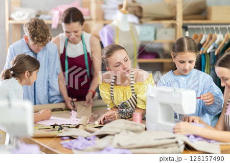 Girl child watches female classmates sew and creating clothes 128157490