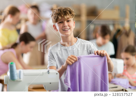 Boy showing stitched fabric during sewing workshop for children Boy showing stitched fabric during sewing workshop for children 128157527