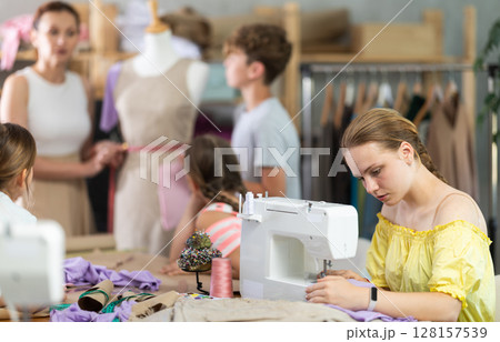 Teen girl child sews during practical lesson at school of young fashion designers Teen girl child sews during practical lesson at school of young fashion designers 128157539