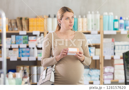 Pregnant woman chooses pills at pharmacy Pregnant woman chooses pills at pharmacy 128157620