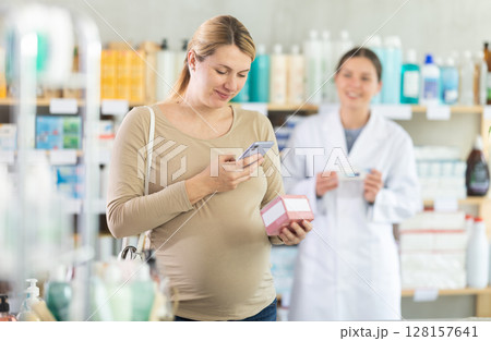 Pregnant woman buyer scans pills qr code with woman pharmacist 128157641