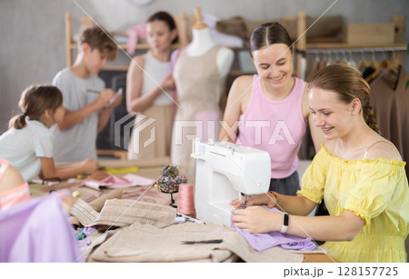 Girl child watches female classmates sew and creating clothes 128157725