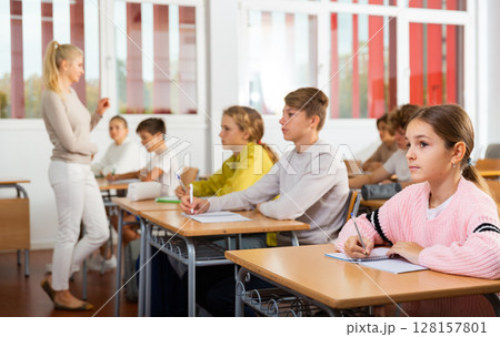Teenagers sitting at desks in classroom during lesson 128157801