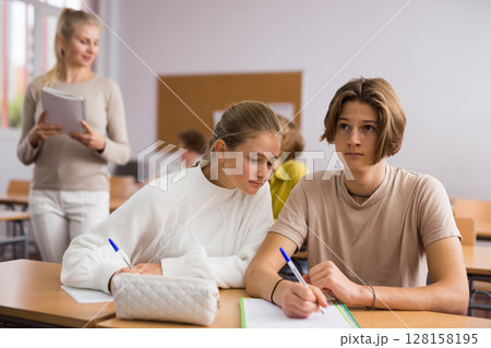 Teenagers doing tasks during lesson in school Teenagers doing tasks during lesson in school 128158195