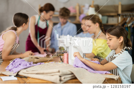 Girl child sews during practical lesson at school of young fashion designers and tailors Girl child sews during practical lesson at school of young fashion designers and tailors 128158197