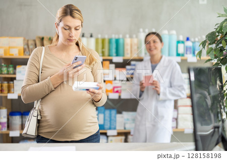 Pregnant woman buyer scans pills qr code with woman pharmacist 128158198